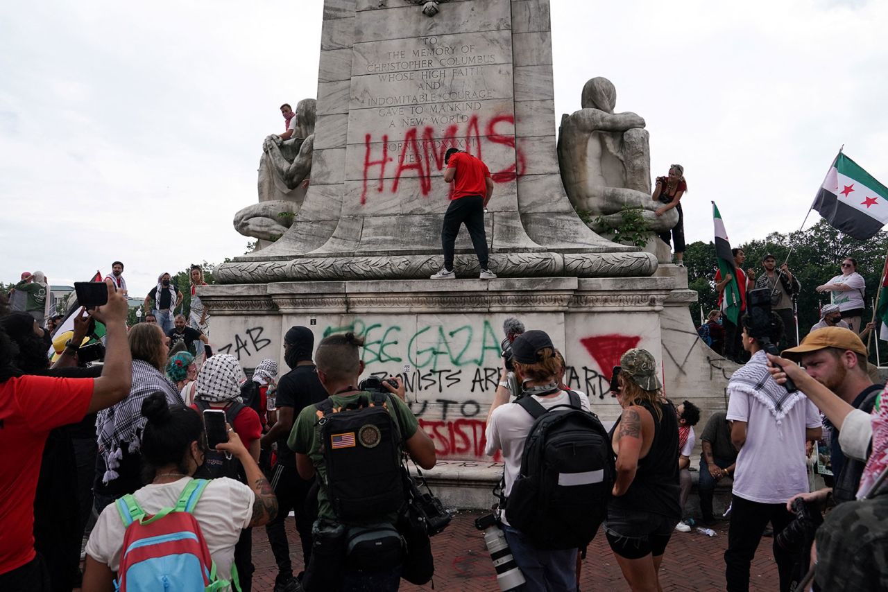 A demonstrator sprays graffiti, including the word "Hamas," on the Christopher Columbus Memorial Fountain at Union Station.