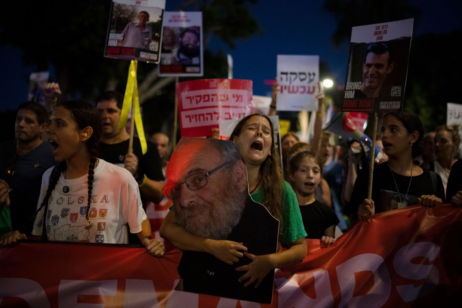 A photo of Alex Dancyg is held by his granddaughter Eliya during a rally in Tel Aviv, Israel, on Tuesday, July 23. Dancyg, a <a href="index.php?page=&url=https%3A%2F%2Fwww.cnn.com%2Fmiddleeast%2Flive-news%2Fisrael-hamas-war-gaza-news-10-20-23%23h_ebcd16da41aea60d601b679d81d95109">world authority on Holocaust history</a>, was among the hostages taken by terror group Hamas in October. The Israel Defense Forces said this week that Dancyg is no longer believed to be alive.