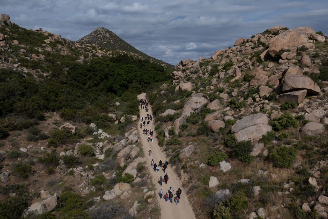 Asylum seeking migrants from China and Turkey climb a hill while looking to surrender to immigration officials, after crossing the border into the U.S. from Mexico in Jacumba Hot Springs, California, on May 20, 2024.