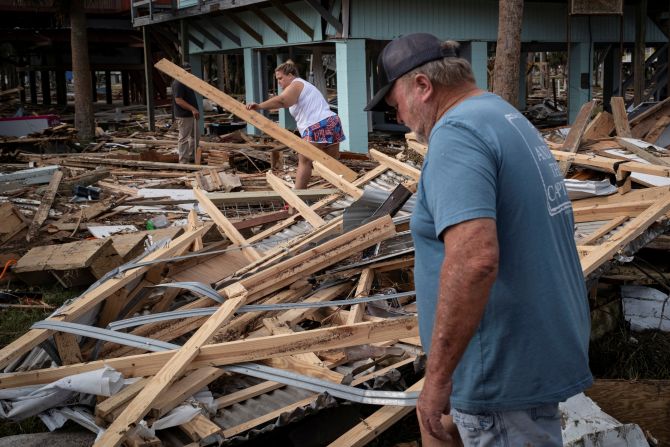 Residents walk among debris from their family's beach house in Horseshoe Beach, Florida, on Saturday.