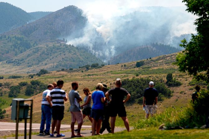 Onlookers gather at a roadblock to watch as a wildfire burns in the mountains near the Ken Caryl Ranch development, southwest of Littleton, Colorado, on July 31, 2024.