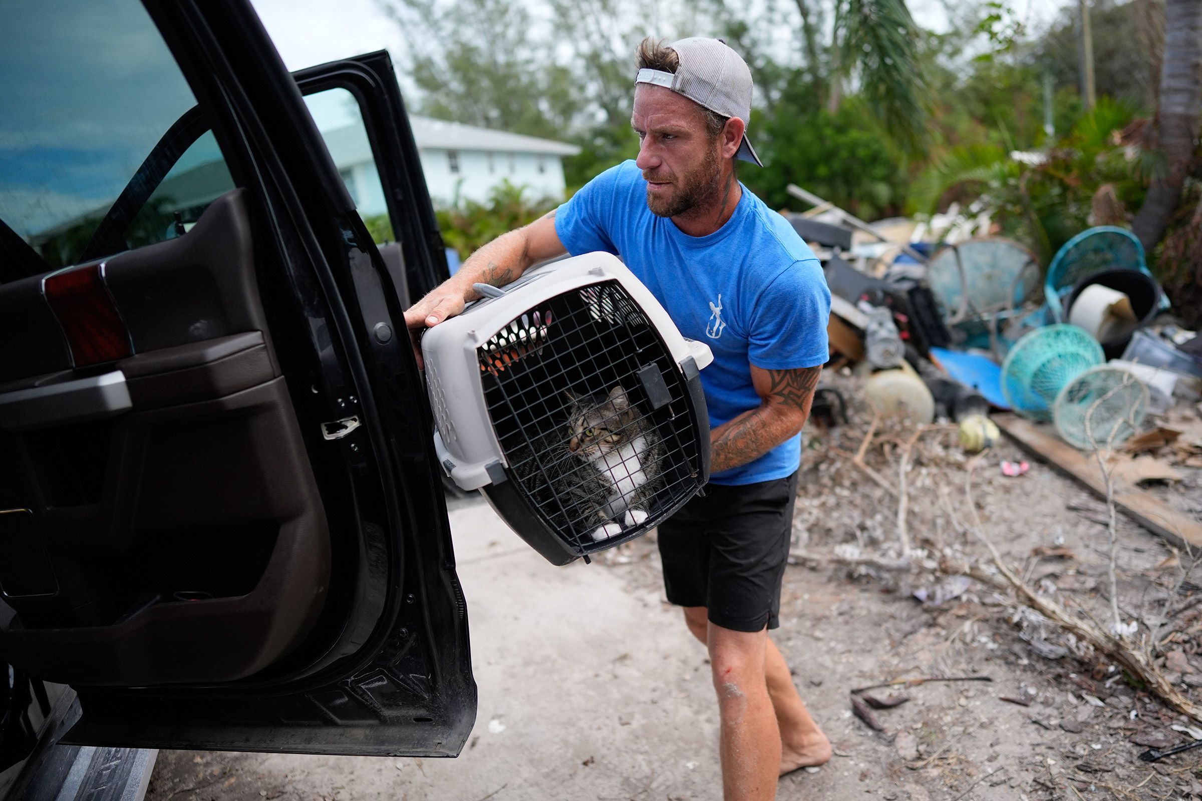 Ted Carlson puts McKenzie, a cat belonging to his friend Evan Purcell, into a pickup truck as they evacuate Purcell's home on Florida's Anna Maria Island on Tuesday, October 8. "This place couldn't handle Helene," Carlson said. "It's all going to be gone."