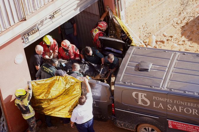 Authorities carry a body into a van in Valencia on Thursday.