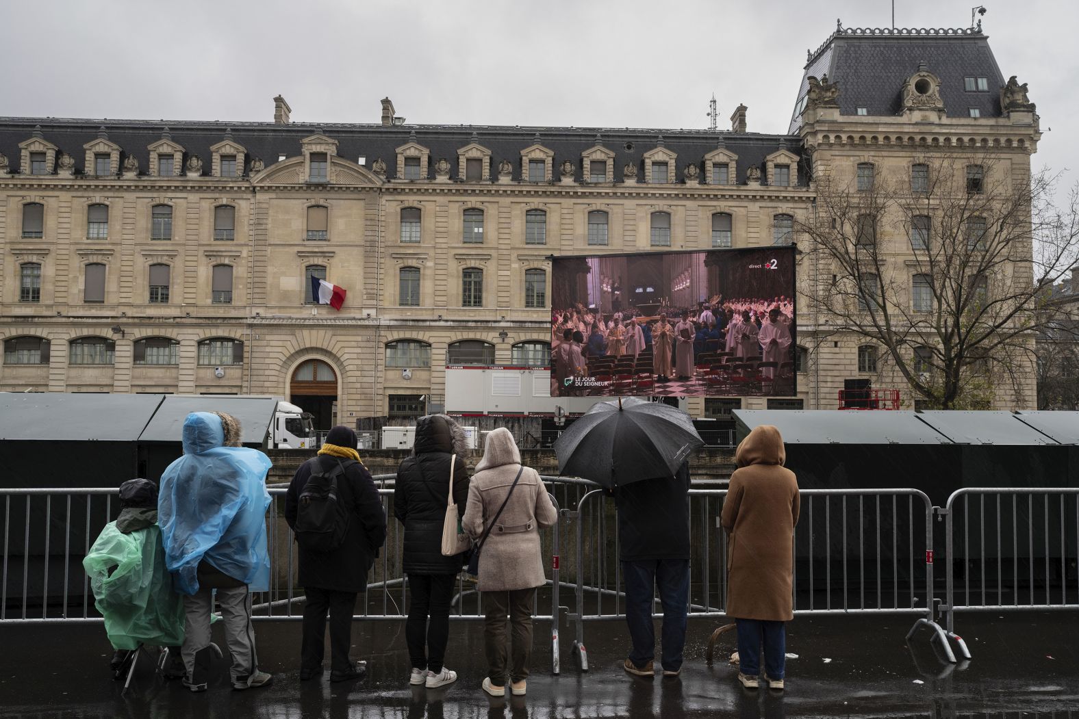 People watch a broadcast of the Mass on a screen outside the cathedral on December 8.