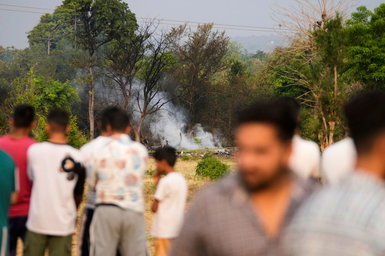 Villagers watch as firefighters spray water on the debris of a downed aircraft near Akhnoor, Indian-administered Kashmir.