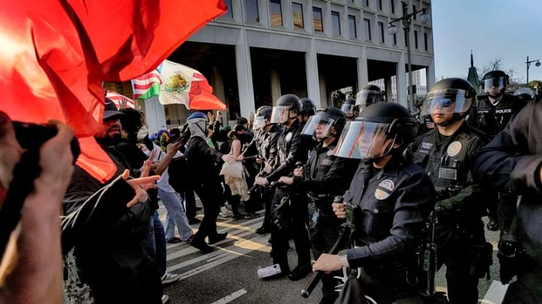 La policía de Los Ángeles, con equipo antidisturbios, forma una línea de escaramuza y hace retroceder a los manifestantes por una calle, lejos de un edificio federal en el centro de Los Ángeles, el 9 de junio.