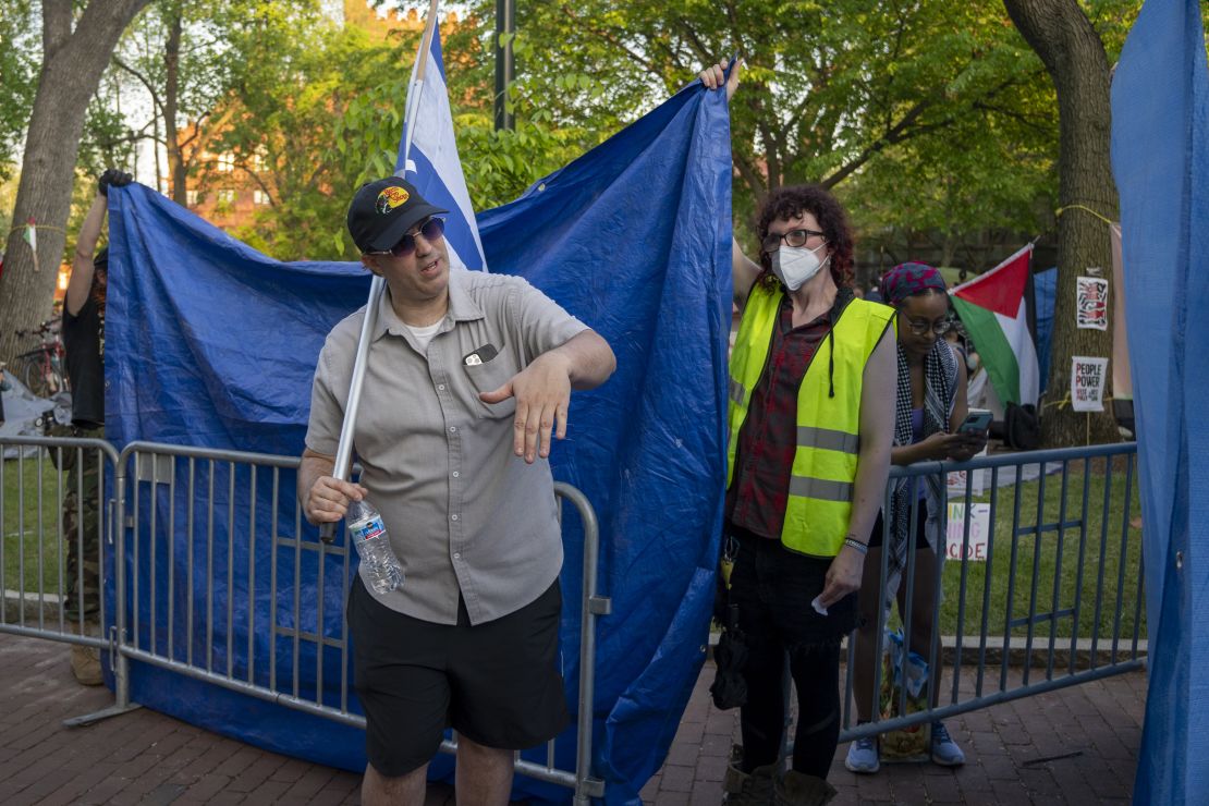 A tarp is held up to shield the encampment from a counter protester.