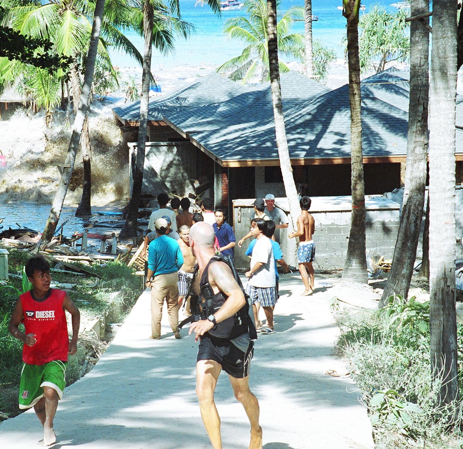 People flee as a tsunami wave crashes ashore on an island in Thailand.