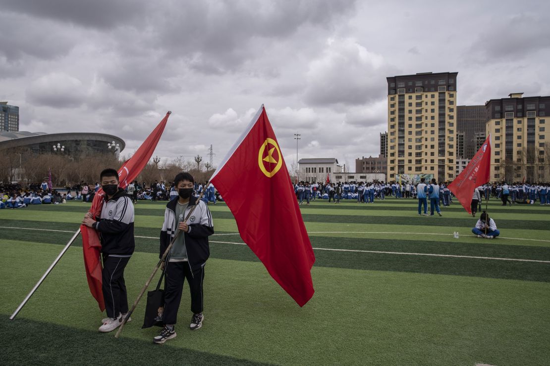 Students hold flags, including the Communist Youth League of China flag, second left, during a city-wide sporting event in Yumen, Gansu province, China, in 2021.