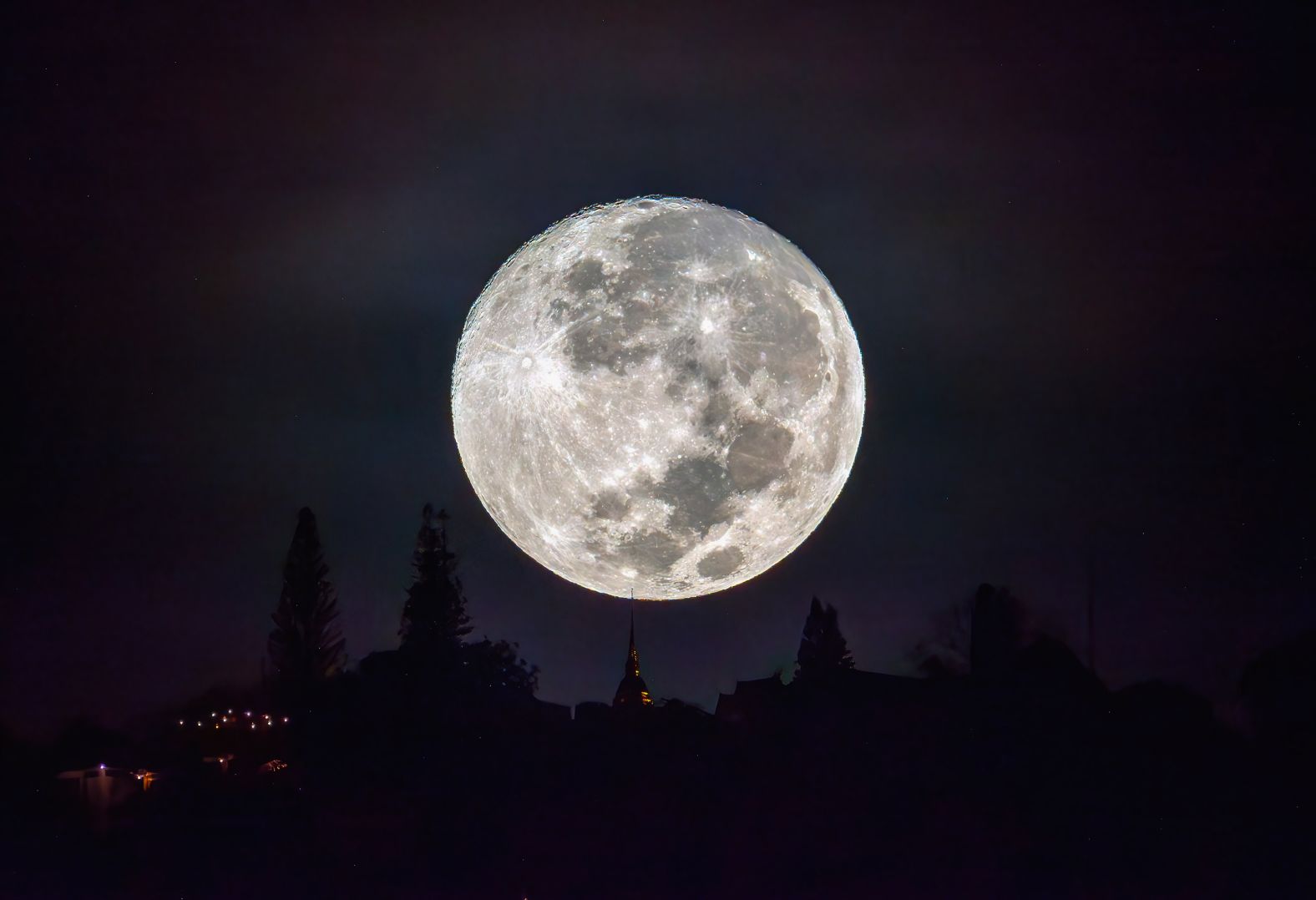 The moon shines above the spire of Wat Phra That Doi Suthep in Chiang Mai, Thailand.