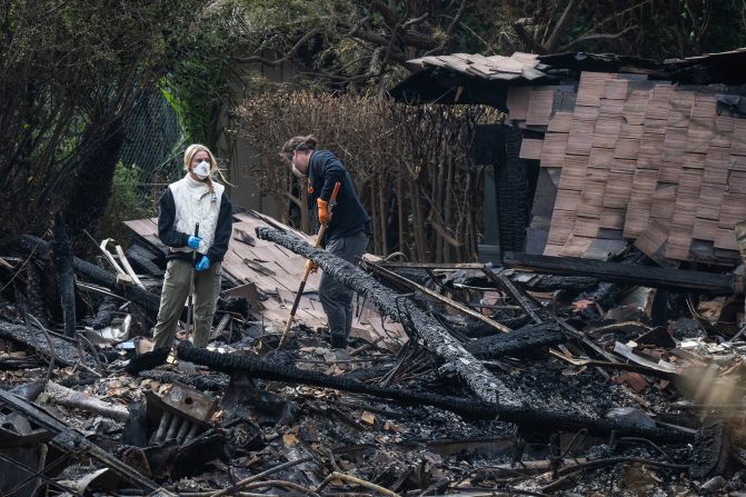 Family members sift through the remains of a home lost in the fire on Wednesday.