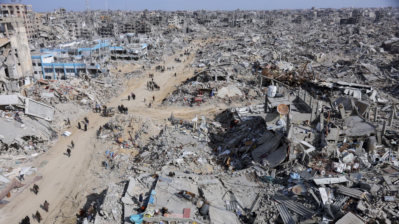 People walk towards their homes through the destroyed streets of Gaza City on January 19, 2025. The ceasefire agreement between Israel and Hamas has allowed displaced individuals to return, though significant destruction remains. (Photo by Abood Abusalama / Middle East Images / Middle East Images via AFP) (Photo by ABOOD ABUSALAMA/Middle East Images/AFP via Getty Images)