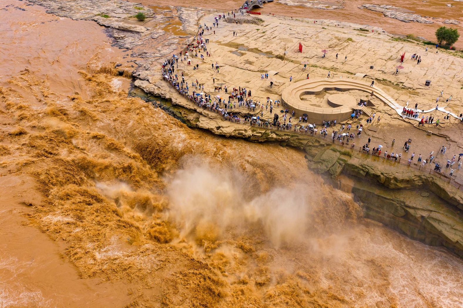 People visit the roaring Hukou Waterfall on the Yellow River in Yan’an, China, on Monday, August 11.