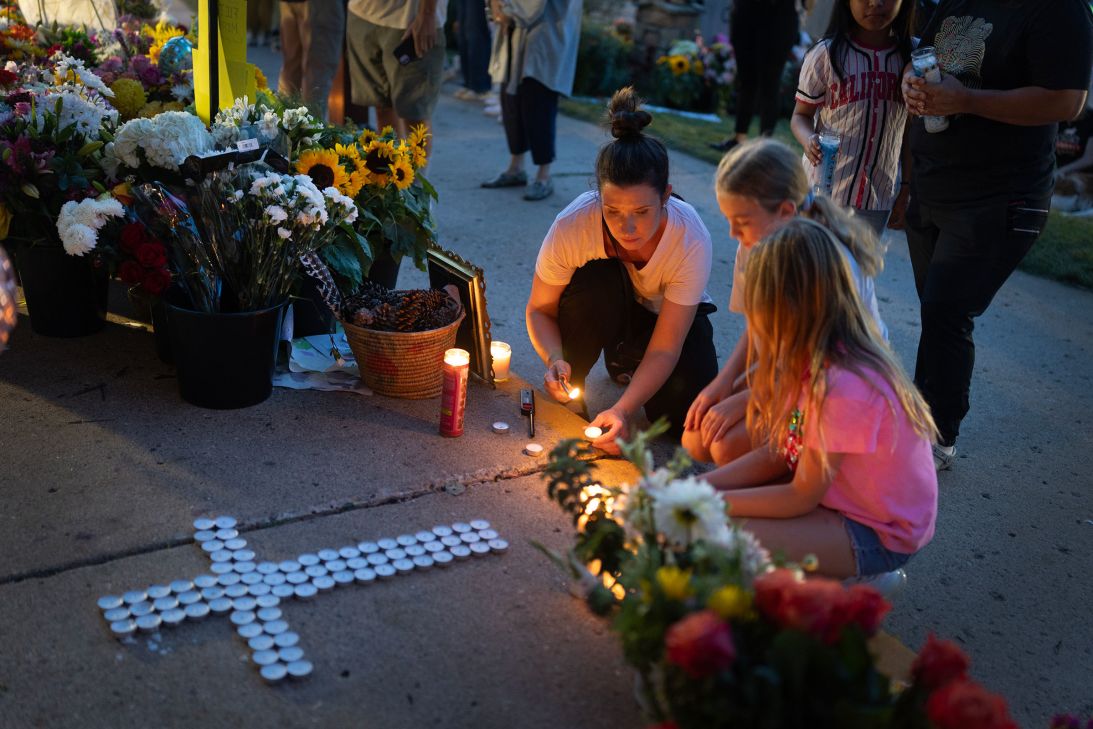 Jen Labanowski, her daughter Lucy, right, and her daughter's friend Cece Degnan, center, light candles at a memorial for shooting victims on Thursday.