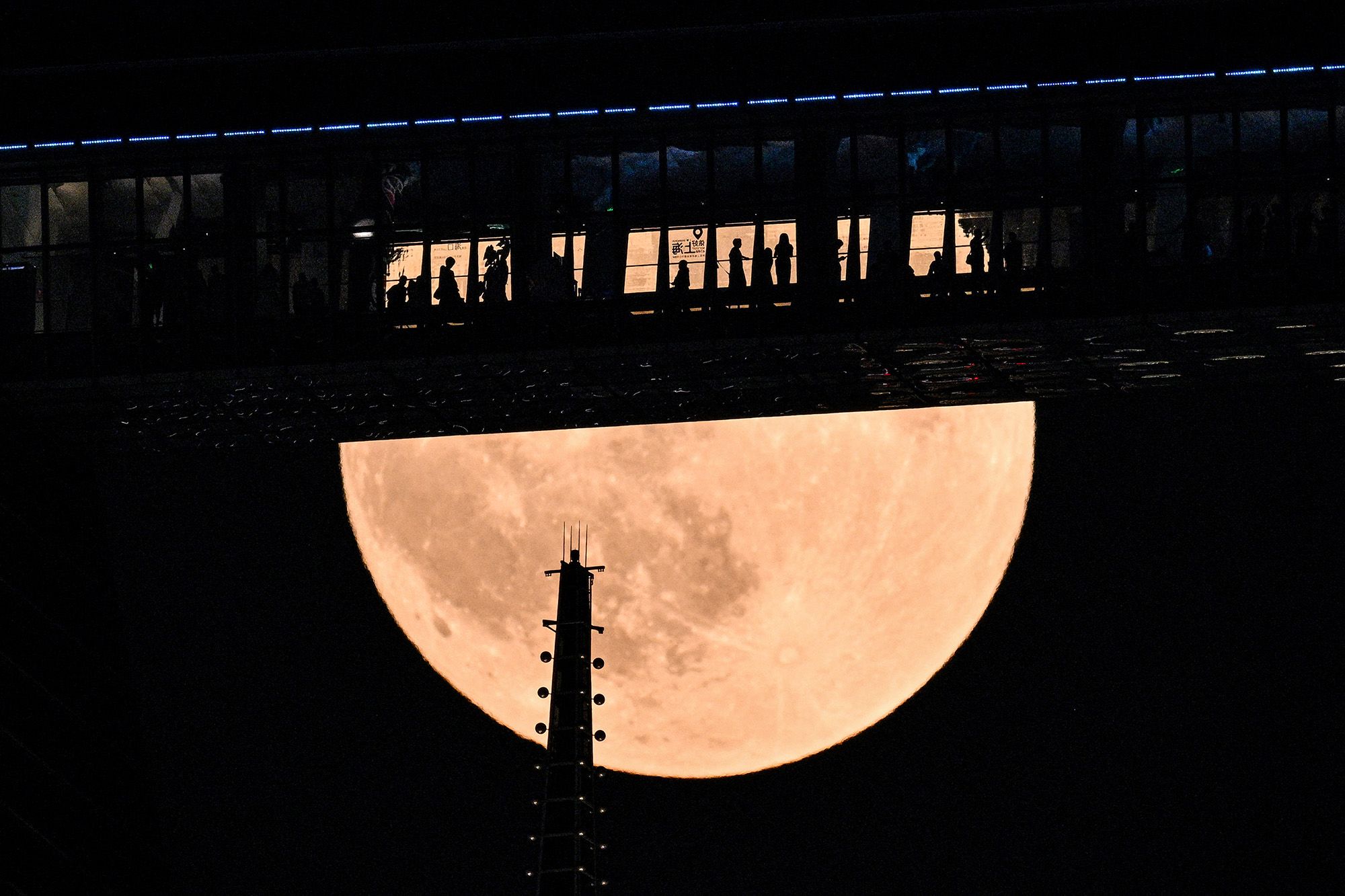 People are seen on a floor of the Shanghai World Financial Centre as the full moon rises above skyscrapers in Shanghai.