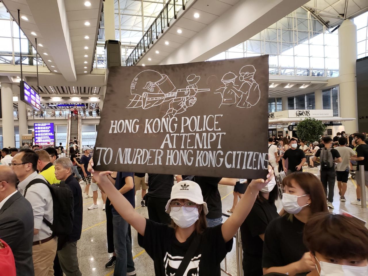 Protesters greet arriving travelers at the airport with signs warning of police brutality.