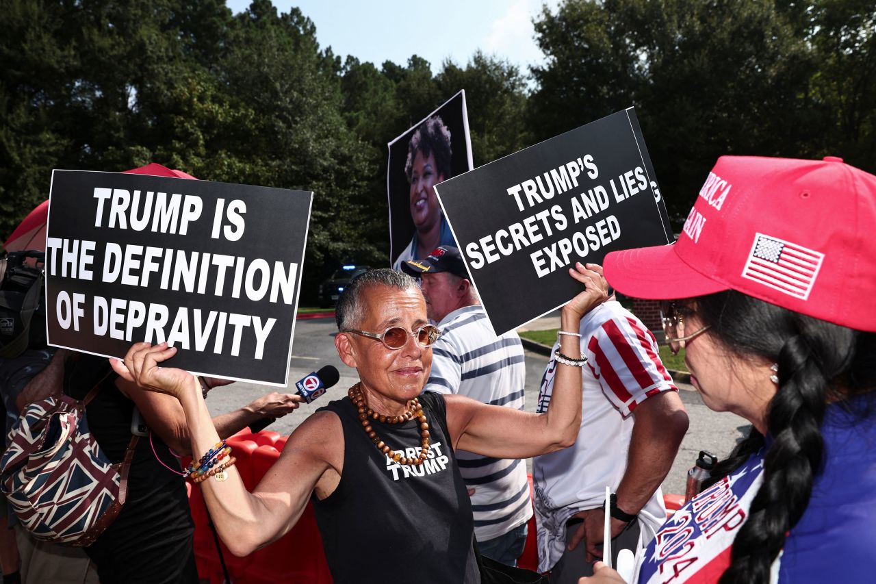 A demonstrator holds anti-Trump banners in front of a supporter of former President Donald Trump near the entrance of the Fulton County Jail on Thursday.