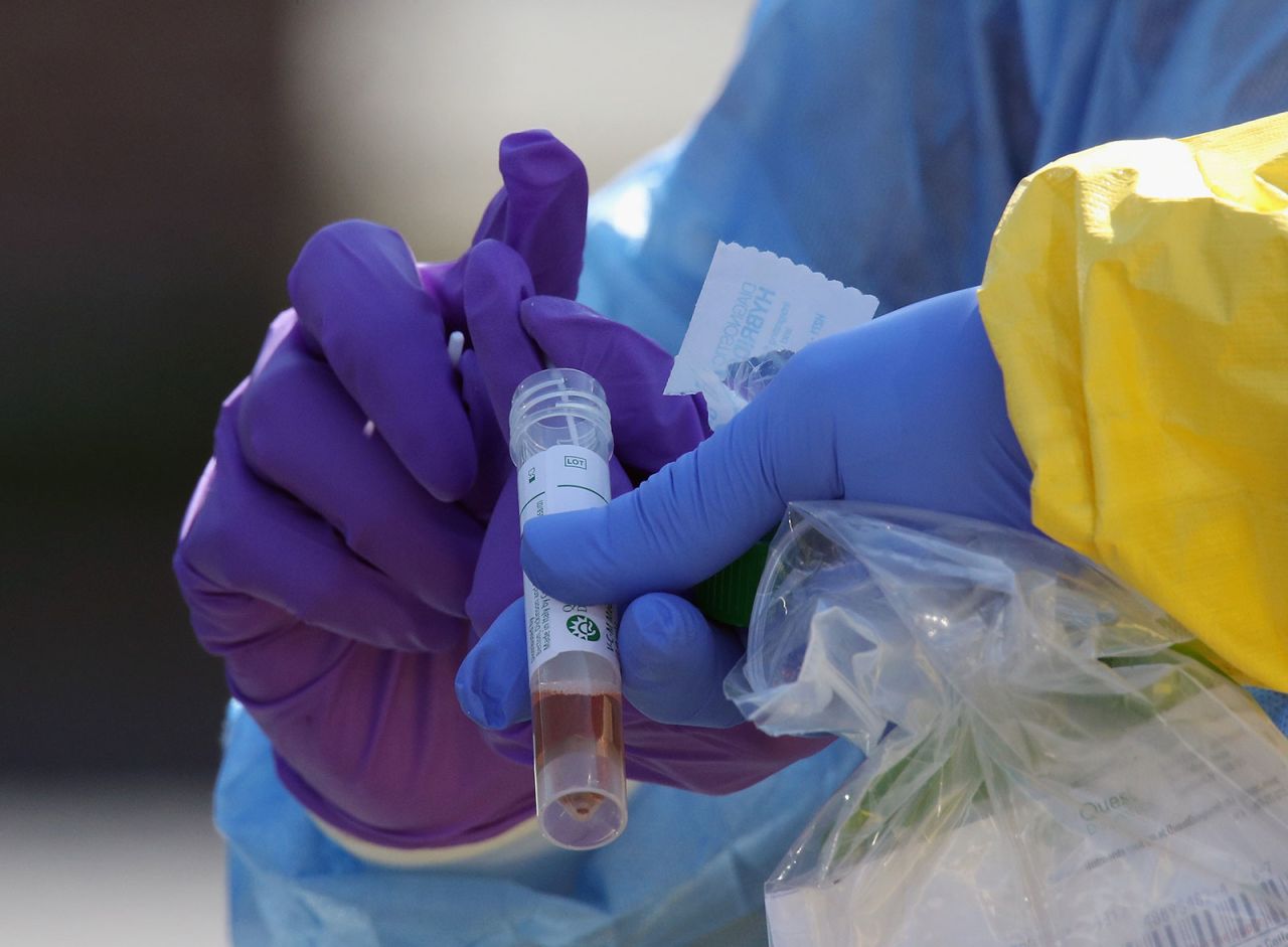 Health care workers administer a coronavirus test at a drive-through testing facility in Jericho, New York, on March 21.