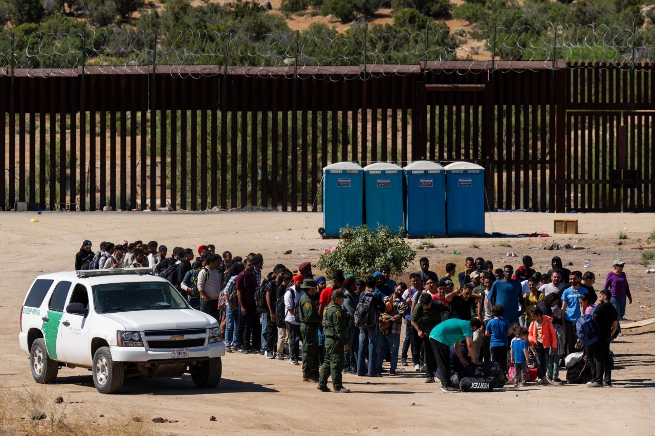 Migrants wait to be processed by US Border Patrol agents after crossing into the US from Mexico on June 14, in Jacumba Hot Springs, California.