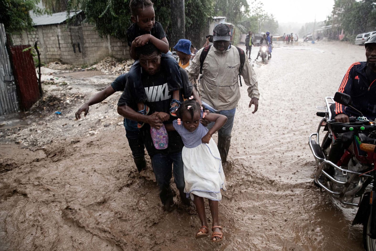 People walk through a flooded street in Petit-Goâve, Haiti, on Thursday, October 30. <a href="index.php?page=&url=https%3A%2F%2Fwww.cnn.com%2F2025%2F10%2F30%2Famericas%2Frescue-efforts-storm-melissa-intl">Hurricane Melissa</a> did not make direct landfall in Haiti, but it caused significant damage there and at least 23 deaths due to severe flooding and landslides.