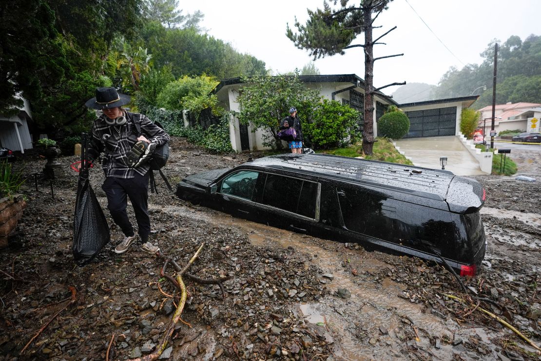 Residents evacuate past damaged vehicles after storms caused a mudslide on Monday in the Beverly Crest area of Los Angeles.