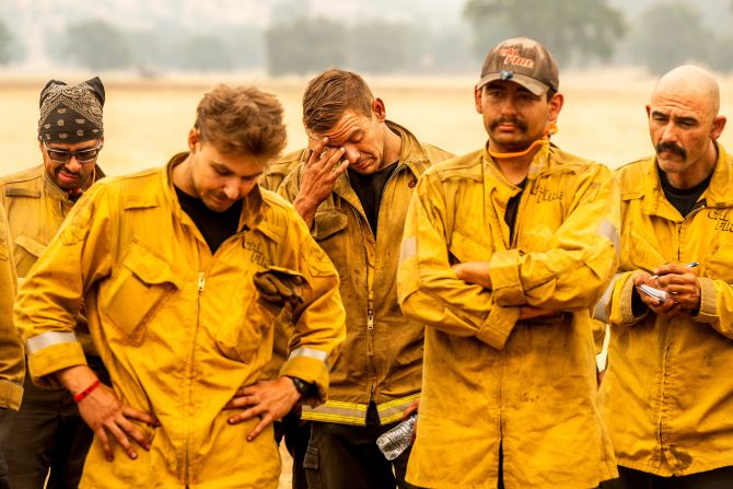 Firefighter Michael Benson, center, rubs his face during a briefing while battling the Park Fire in Tehama County, California on July 27, 2024.