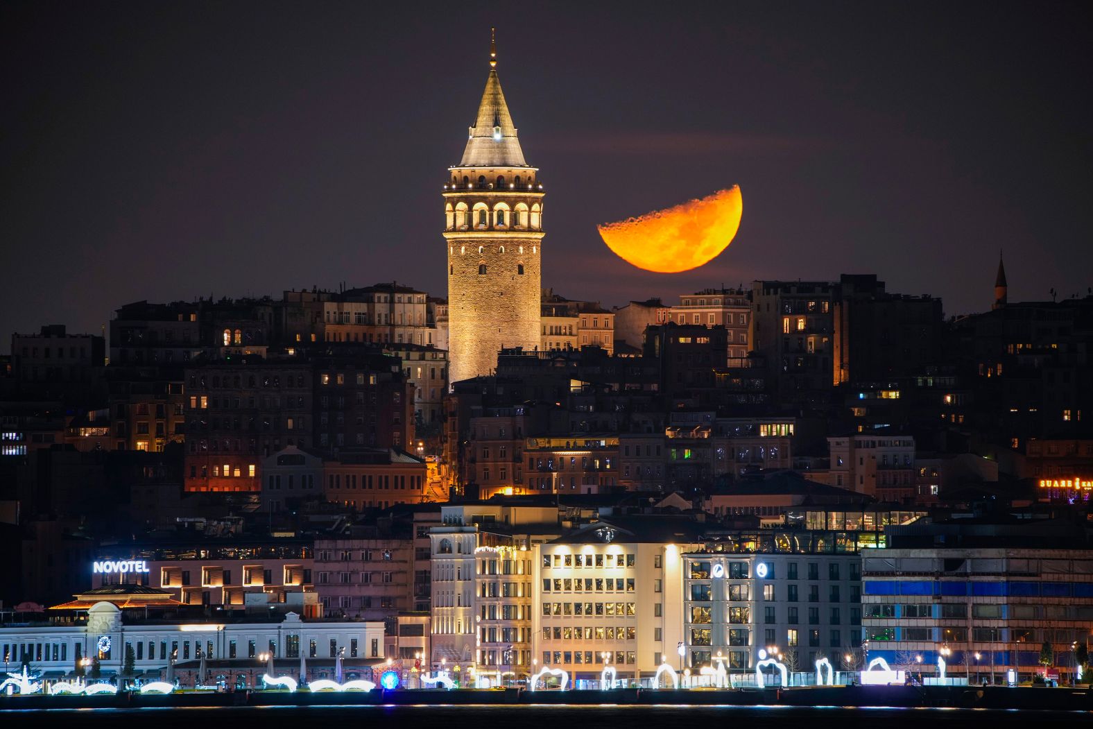 A half moon is seen next to the Galata Tower in Istanbul on Tuesday, January 7.