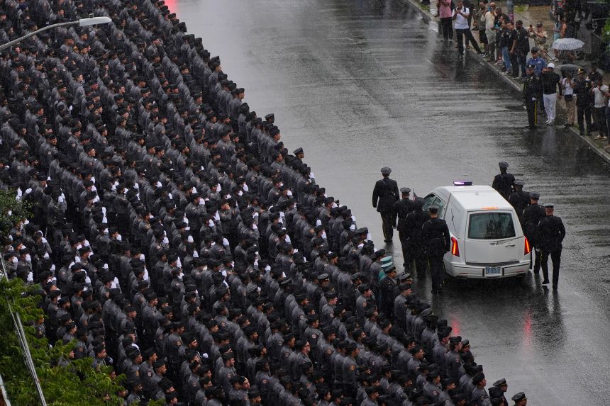 NYPD officers salute as the hearse carrying the casket of NYPD officer Didarul Islam passes, following his funeral on July 31.