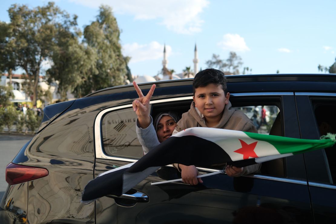 A boy holds the Syrian opposition flag as tens of thousands of people gather in Damascus to celebrate the fall of the Assad regime.