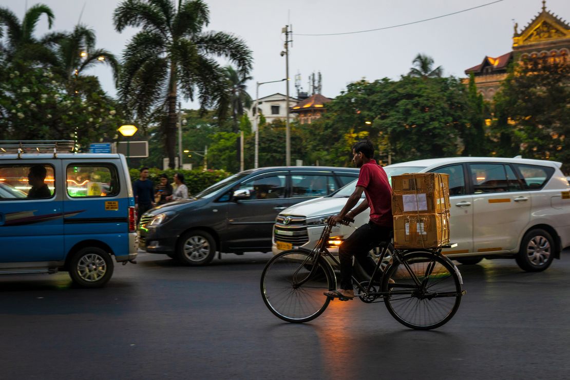 A delivery worker rides his bicycle through the traffic in Colaba, Mumbai, on April 17, 2024.
