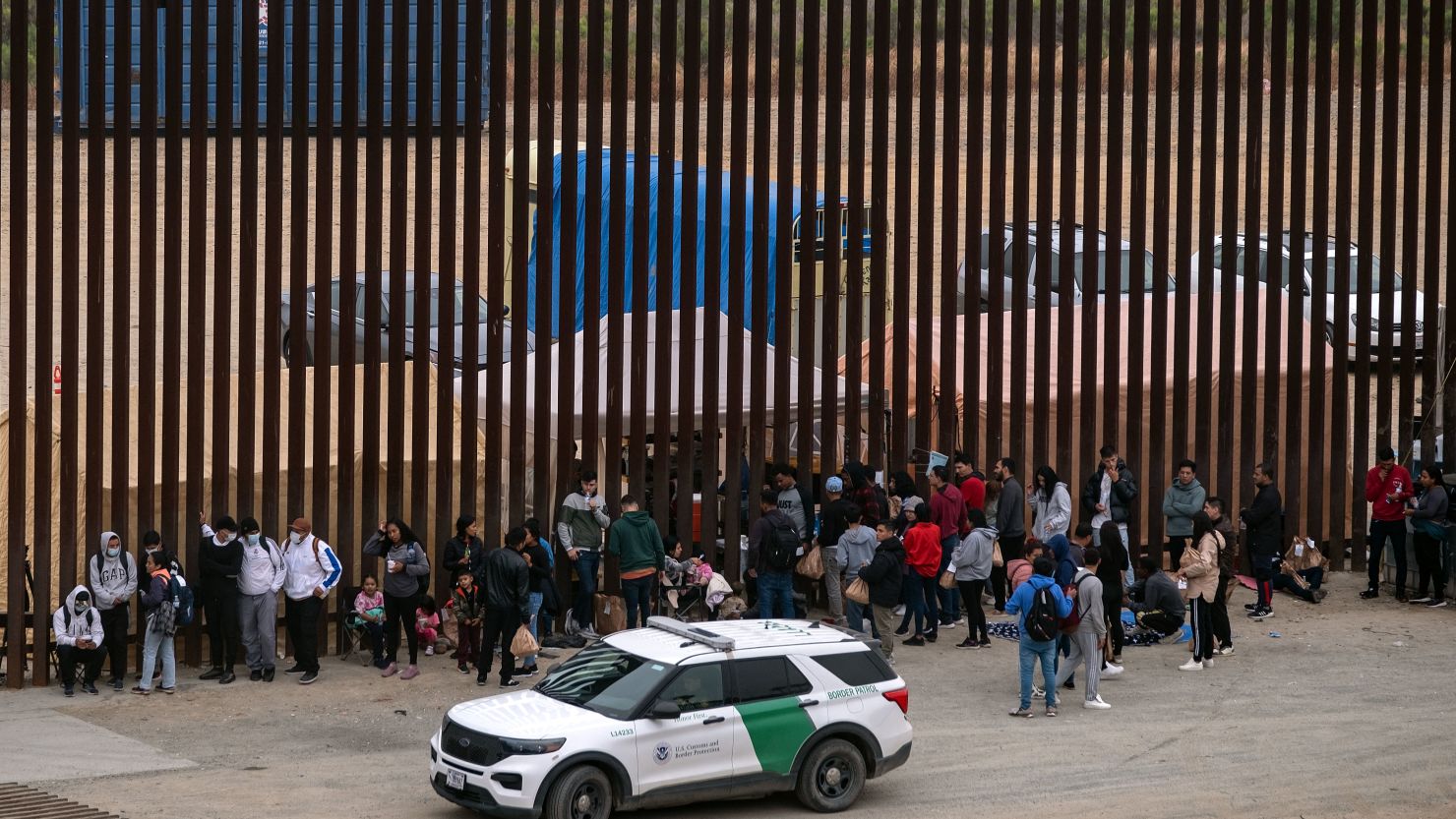 Migrants and asylum seekers wait to be processed by the Border Patrol between fences at the US-Mexico border seen from Tijuana, Baja California state, Mexico, on June 5, 2024.