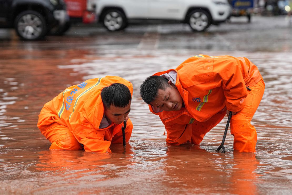 Workers dredge a sewer in a flooded street in Hunan province's Changsha on June 24.