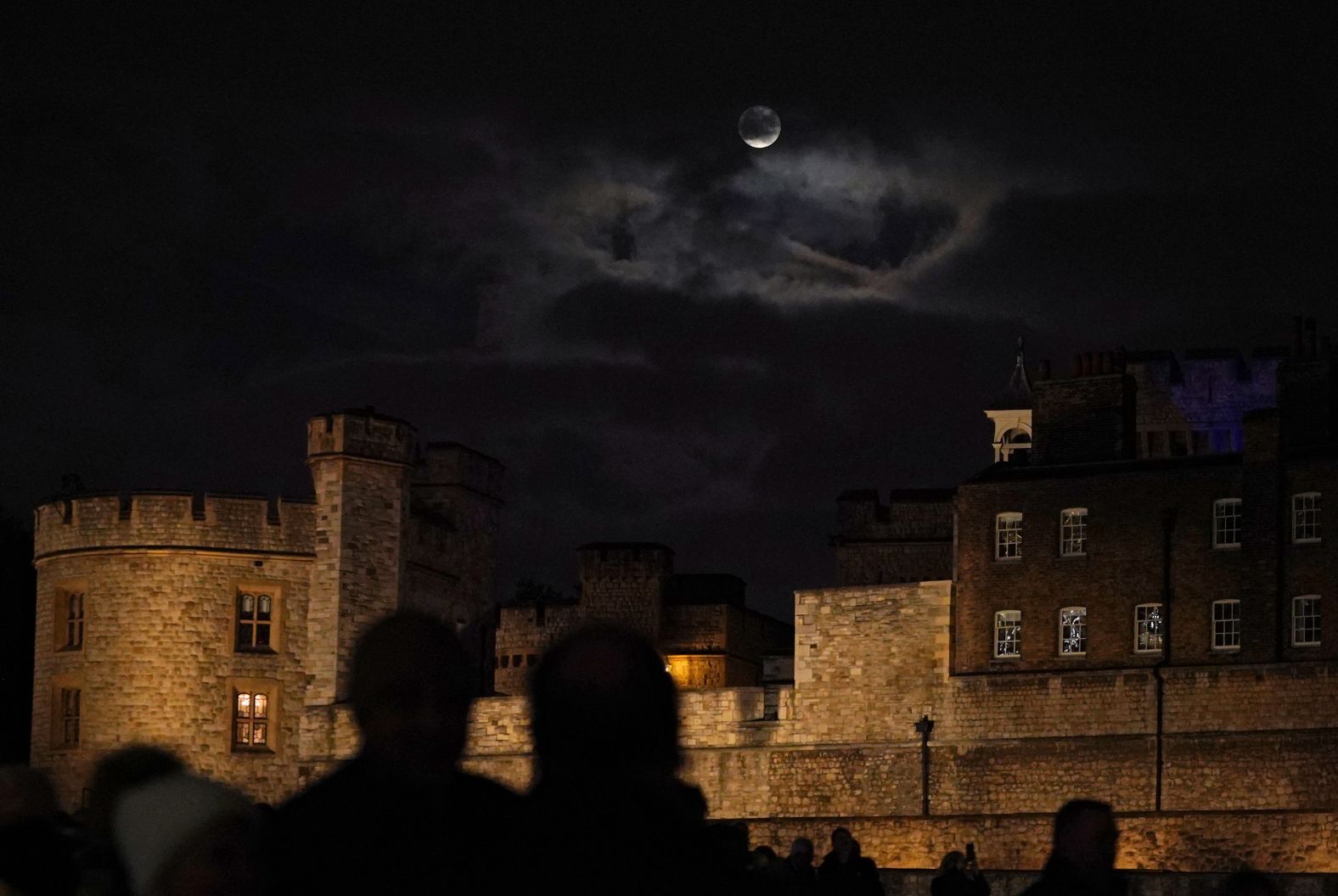 Clouds partially cover the supermoon, as seen above the Tower of London in England.