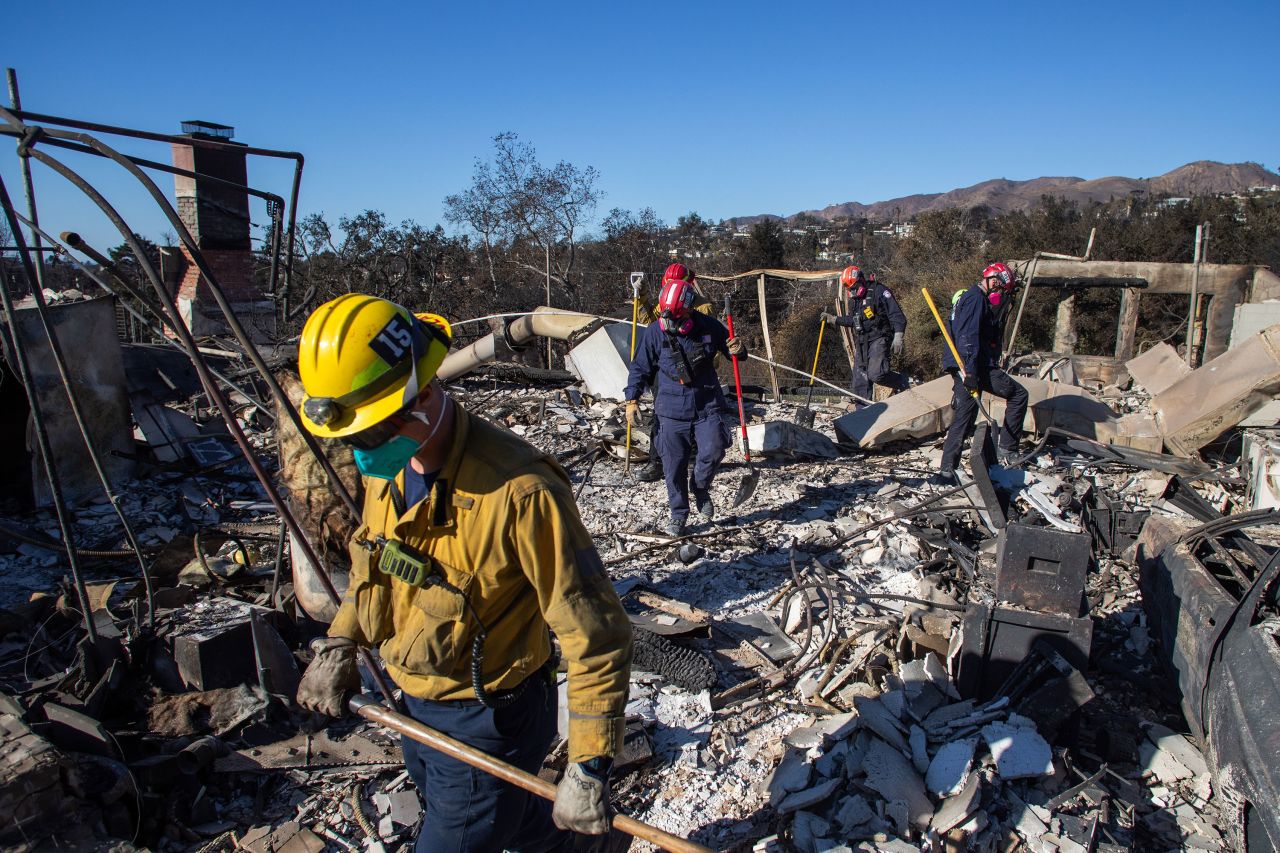 Firefighters inspect a destroyed house Thursday in the Pacific Palisades neighborhood.