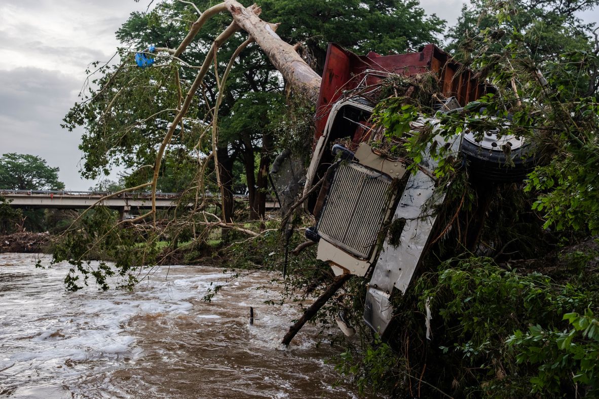 A truck is impaled by a tree on the banks of the Guadalupe River on Saturday.
