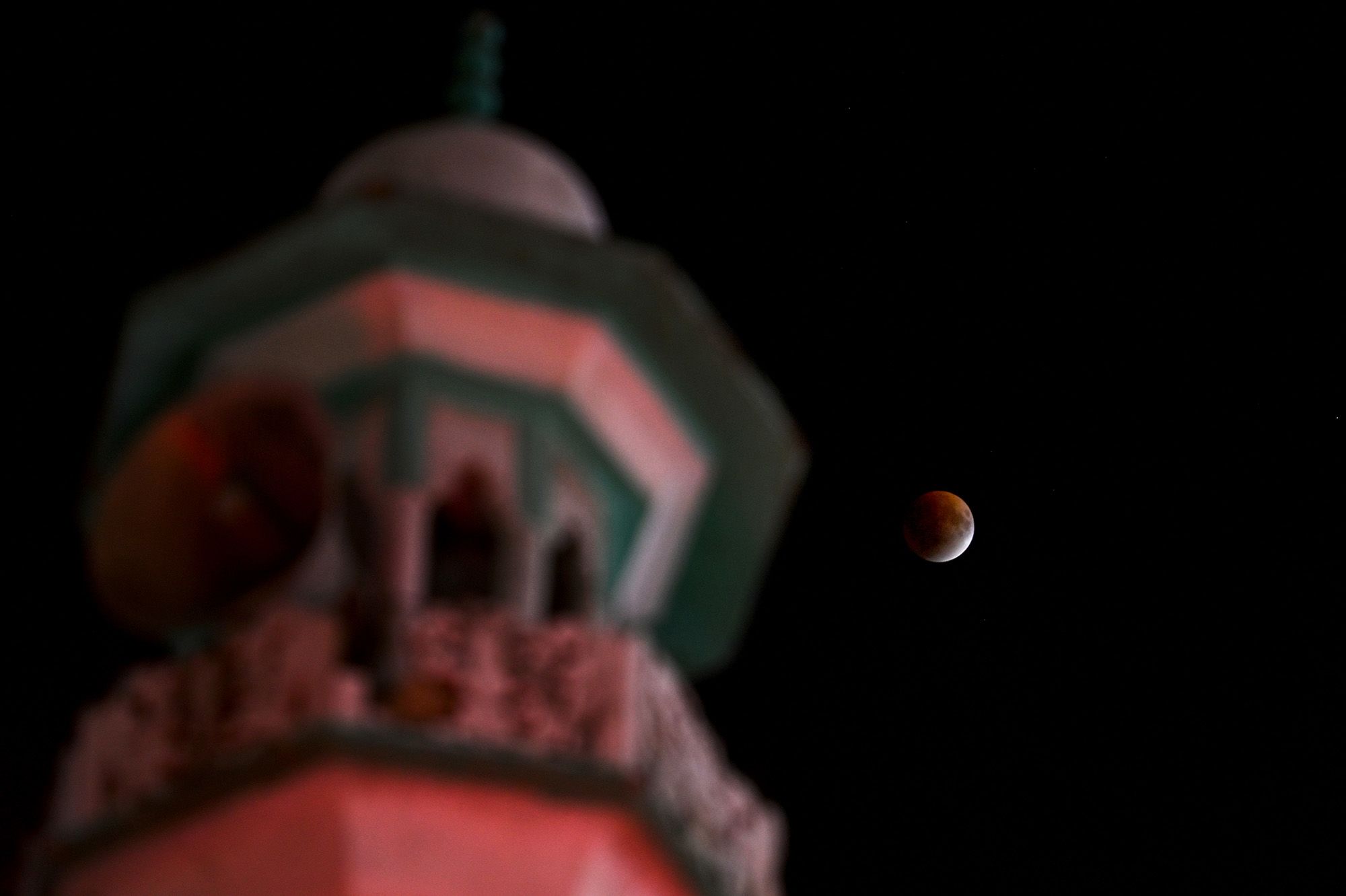 The blood moon is pictured above a mosque in New Delhi on Sunday.