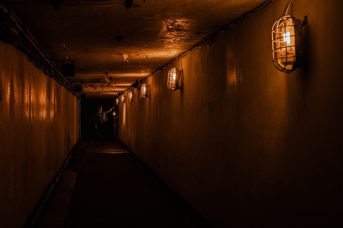 Visitors enter the installation via a narrow, dimly-lit tunnel built into the mountainside.