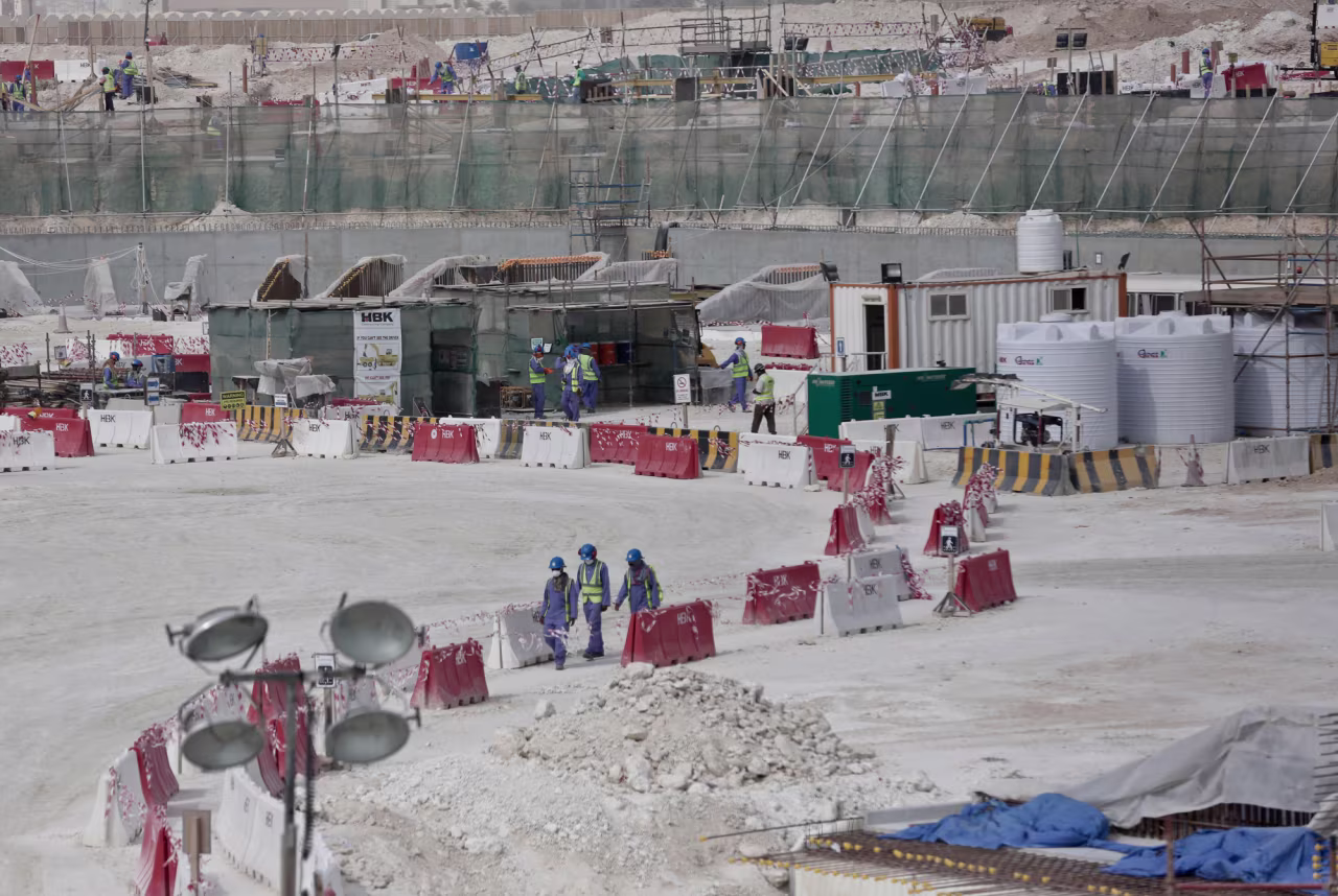 Workers walk between safety barricades at Al-Wakrah Stadium that is under construction for the 2022 World Cup in Doha, Qatar on May 4, 2015.