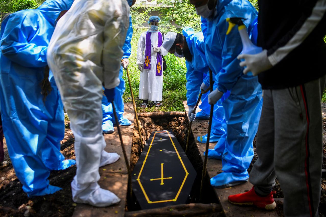 Volunteers from a Muslim and a Christian group lower the coffin of a Covid-19 victim at a cemetery in Pune, India, on September 7.