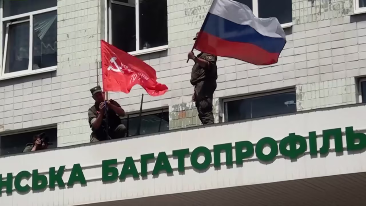 This image released by the People's Militia of the Luhansk People's Republic on July 3, shows their forces with Soviet and Russian national flags on a government building as they capture the city of Lysychansk, in the Luhansk region of eastern Ukraine.