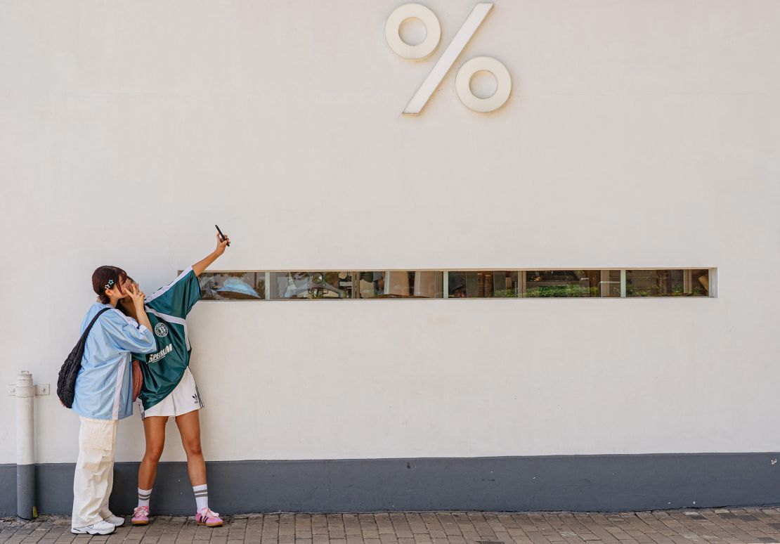 Girls take pictures in front of a Kennedy Town district cafe in Hong Kong.