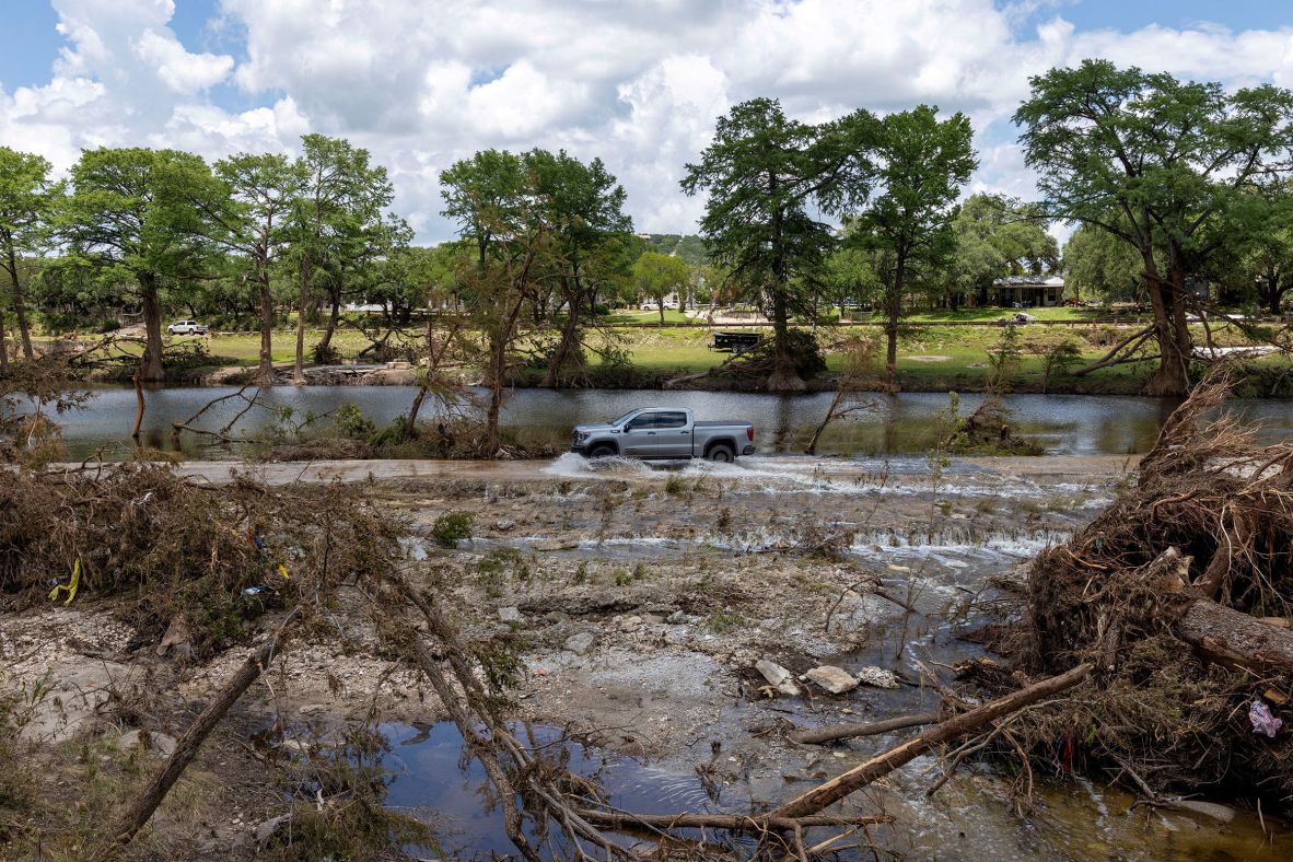 A vehicle drives through a road in Hunt, still flooded by the waters of the Guadalupe River, on Wednesday.