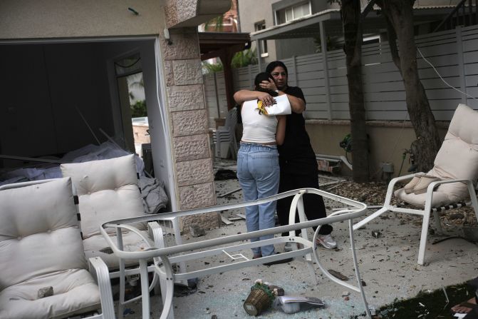 People embrace outside their damaged home in Rishon Lezion on Saturday.