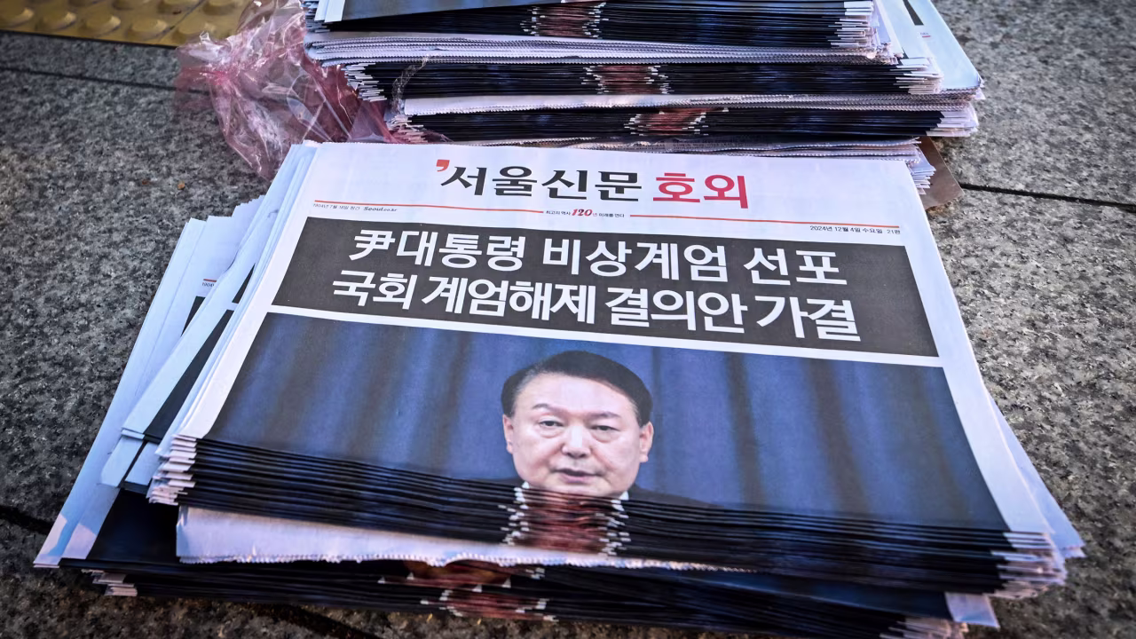 Newspapers headlining Yoon's short-lived attempt at martial law are displayed at a subway gate.