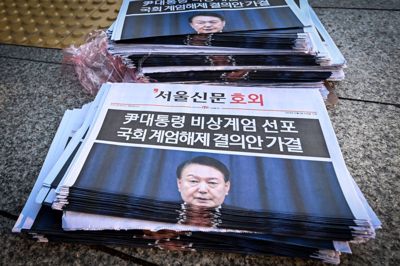 Newspapers headlining Yoon's short-lived attempt at martial law are displayed at a subway gate.