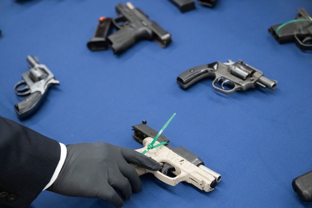 A member of law enforcement handles firearms that were recovered during the arrests of an alleged DC-based drug trafficking organization, prior to a press conference announcing the investigation at the Office of the US Attorney in Washington, DC, on August 26.