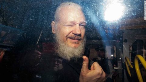 Julian Assange gives a thumbs up to onlookers from inside a police van in London on Thursday.