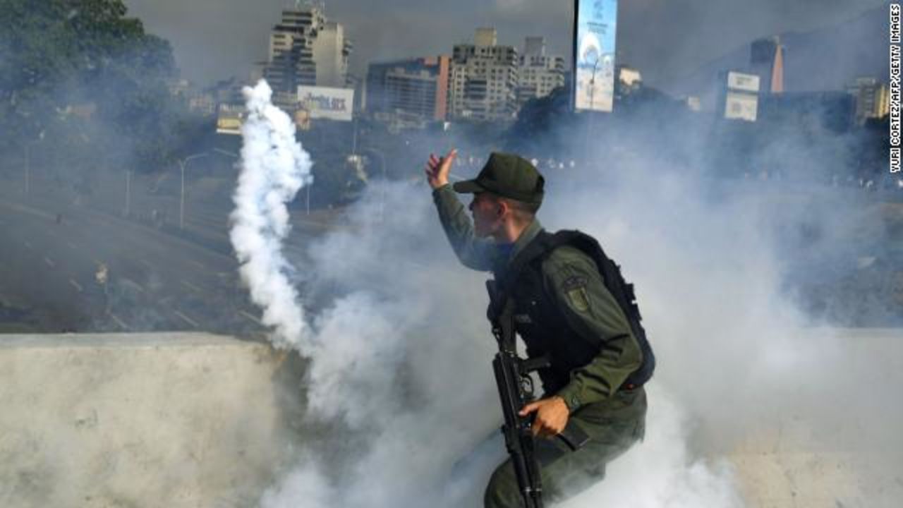 A member of the Bolivarian National Guard supporting Venezuelan opposition leader and self-proclaimed acting president Juan Guaido throws a tear gas canister during a confrontation with guards loyal to President Nicolas Maduro's government in front of La Carlota military base in Caracas.