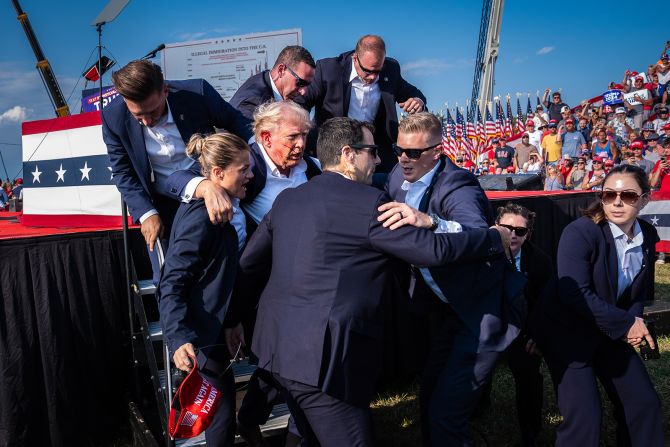 <strong>"Attempted Assassination of Donald Trump."</strong> Members of the United States Secret Service help Republican presidential nominee <a href="index.php?page=&url=https%3A%2F%2Fwww.cnn.com%2Fpolitics%2Fpresident-donald-trump-47">Donald Trump</a> off stage moments after a bullet from an <a href="index.php?page=&url=https%3A%2F%2Fwww.cnn.com%2F2024%2F09%2F16%2Fpolitics%2Fdonald-trump-recounts-apparent-assassination-attempt%2Findex.html">attempted assassin</a> hit his ear during a campaign rally in Butler, Pennsylvania, United States, on July 13, 2024. Regional winner, North and Central America.