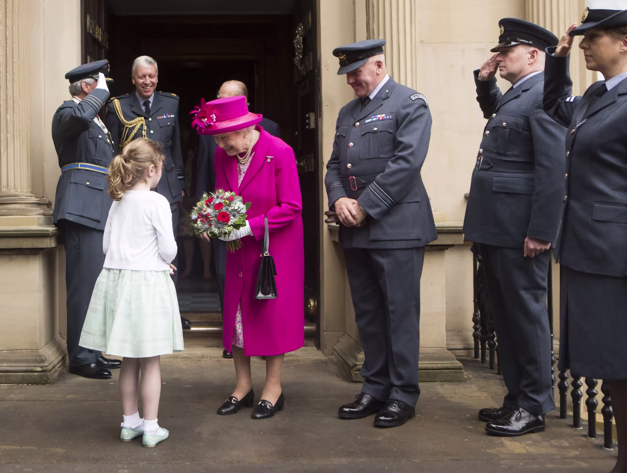 Queen Elizabeth II receives a posy of flowers from Charlotte Murphy during a visit to the headquarters of the Royal Auxiliary Air Force's 603 Squadron on July 4, 2015 in Edinburgh, Scotland.